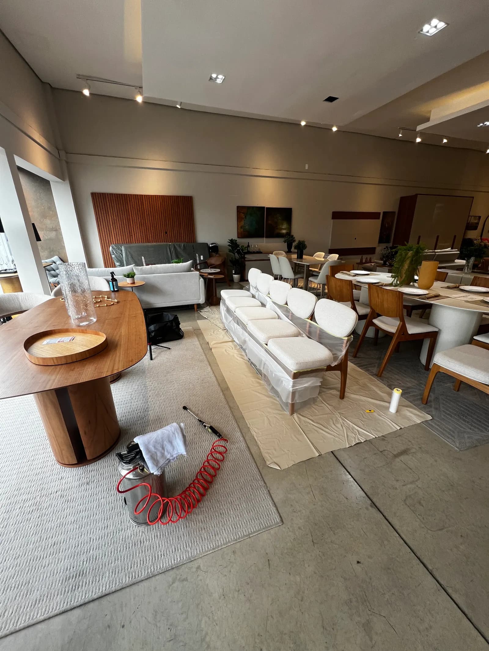 Sofá de cinco lugares protegido com plástico durante serviço da Aurum Clean em showroom de loja de móveis